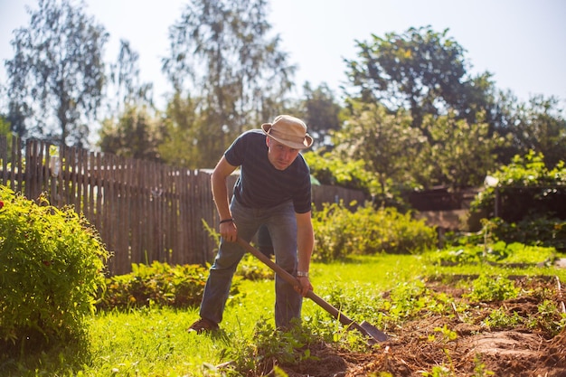 Foto el agricultor excava el suelo en el huerto preparando el suelo para plantar verduras concepto de jardinería trabajo agrícola en la plantación