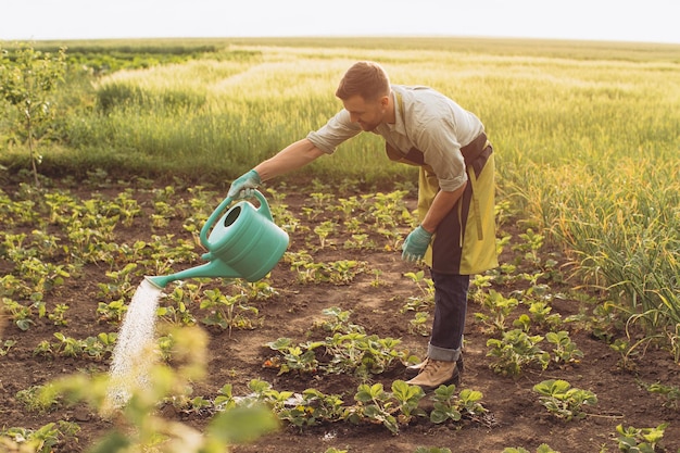 El agricultor feliz riega las camas y trabaja en el jardín