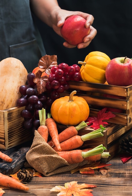 Agricultor con frutas y verduras ecológicas en otoño. Agrícola en la cosecha cornucopia en la temporada de otoño y el día de acción de gracias.