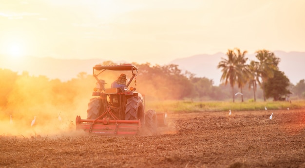 Agricultor en gran tractor en la tierra para preparar el suelo