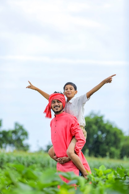 Agricultor indiano brincando com seu filho em campo verde