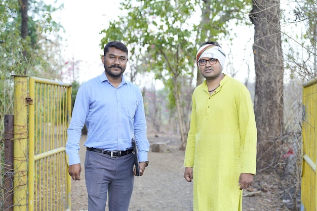 Agricultor indiano com jovem banqueiro indiano no quintal de casa