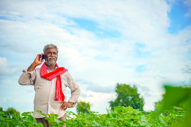 Agricultor indiano falando no celular no campo de agricultura