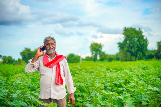 Agricultor indiano falando no celular no campo de agricultura