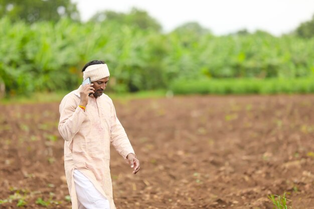 Agricultor indiano falando no celular no campo de agricultura