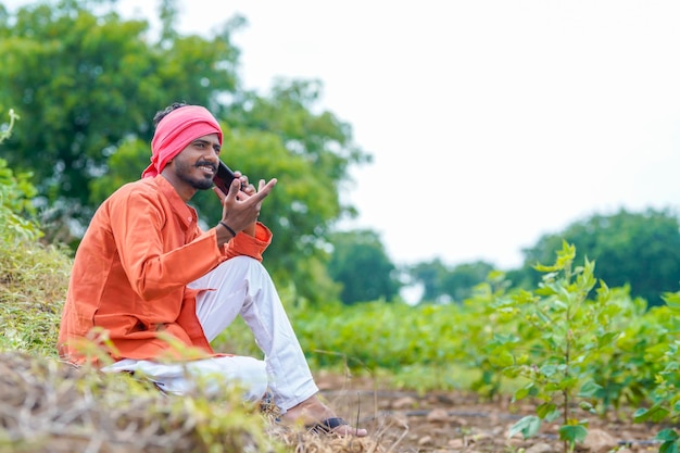 Agricultor indiano falando no smartphone no campo agrícola