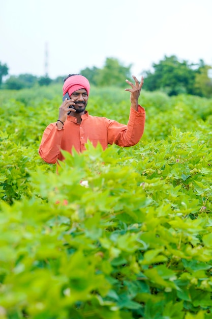 Agricultor indiano falando no smartphone no campo agrícola