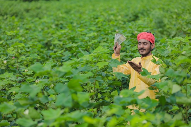 Agricultor indiano mostrando dinheiro em campo de algodão