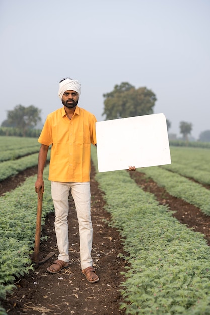 Agricultor indiano mostrando quadro branco no campo agrícola