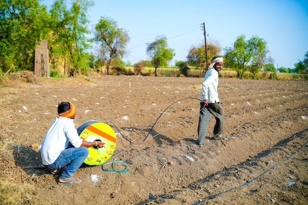 Agricultor indiano ou trabalho de tubo de irrigação por gotejamento montar no campo agrícola. cena rural.