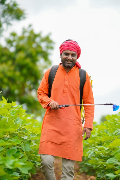 Agricultor indiano pulverizando pesticida em um campo de algodão.