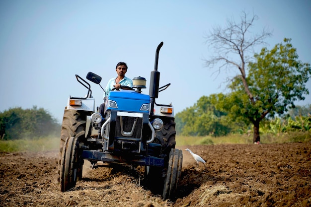 Agricultor indiano trabalhando com trator no campo agrícola.