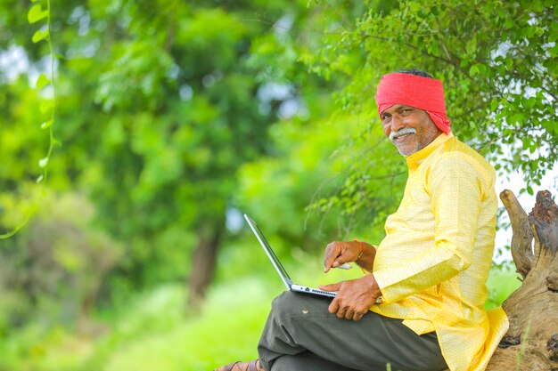 Agricultor indiano usando laptop no campo