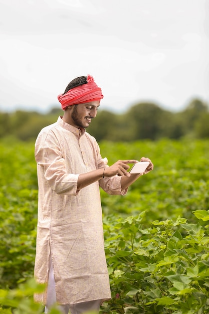 Agricultor indiano usando smartphone no campo de agricultura.