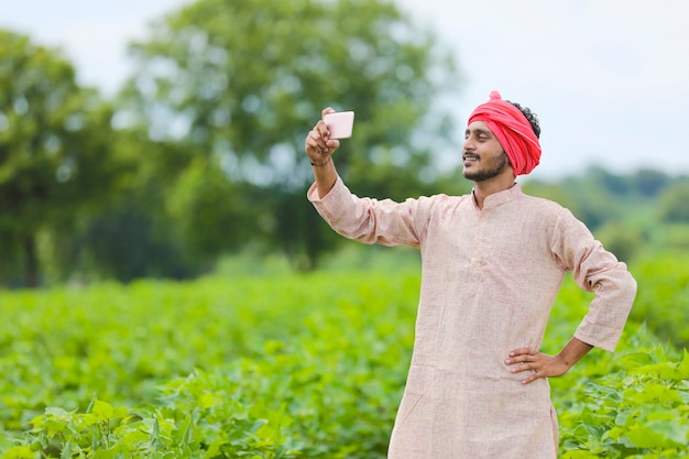 Agricultor indiano usando smartphone no campo de agricultura.