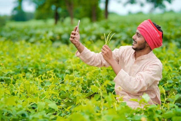 Agricultor indiano usando smartphone no campo de agricultura.