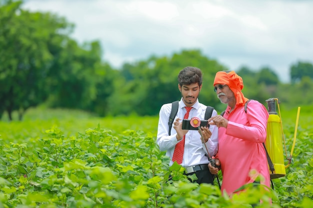 Agricultor indio discutiendo con un agrónomo en la granja y recopilando información