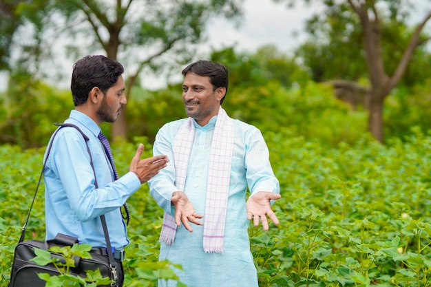 Agricultor indio discutiendo con un agrónomo en la granja y recopilando información