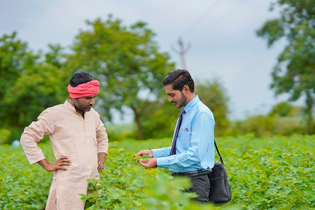 Agricultor indio discutiendo con un agrónomo en la granja y recopilando información