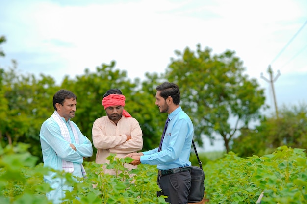 Agricultor indio discutiendo con un agrónomo en la granja y recopilando información