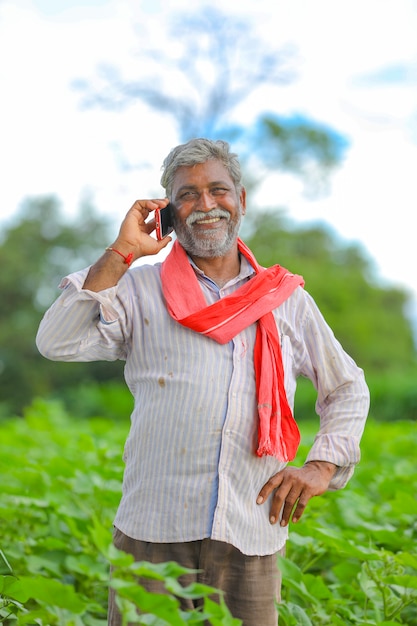 Agricultor indio hablando por teléfono móvil en el campo agrícola