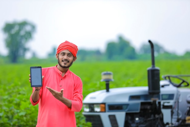 Agricultor indio mostrando una pantalla móvil en el campo agrícola