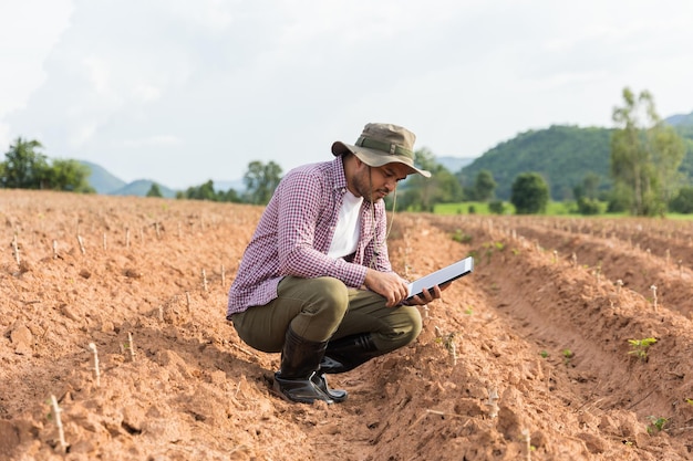 Agricultor inteligente que utiliza una tecnología para estudiar y desarrollar la agricultura. El agricultor que usa tabletas para probar la calidad del crecimiento de las plántulas.