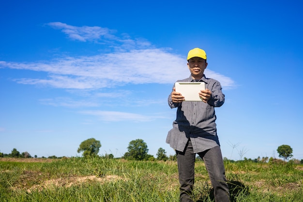 El agricultor inteligente usa una tableta para monitorear y analizar los cultivos en su granja durante un día soleado.