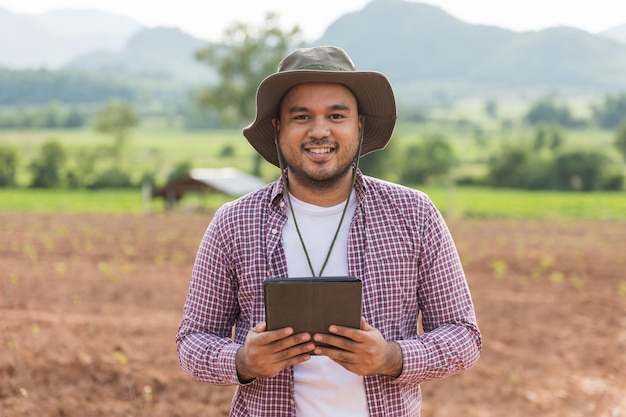 Agricultor inteligente usando uma tecnologia para estudar e desenvolver agricultura. O agricultor usando tablet para testar a qualidade de crescimento de mudas.