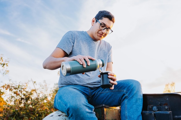 Agricultor latino tomando mate e relaxando, em espaço rural, em cima de um velho trator.