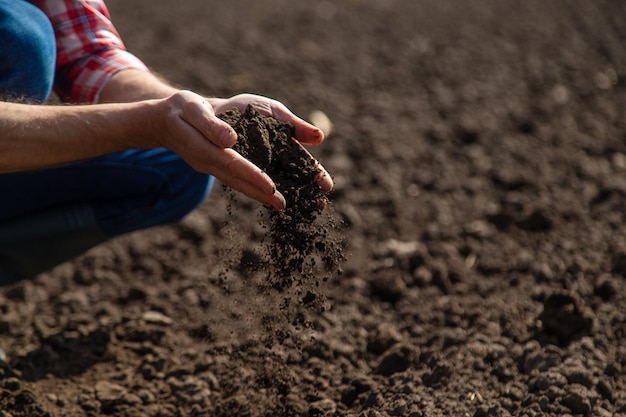 Foto agricultor masculino en el campo revisa el suelo enfoque selectivo