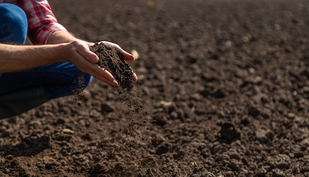 Foto agricultor masculino no campo verifica o foco seletivo do solo