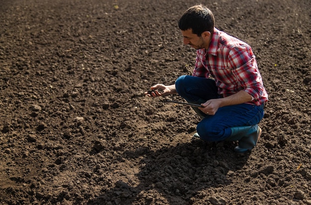 Agricultor masculino no campo verifica o foco seletivo do solo