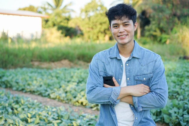 Agricultor (proprietário) homem cruzando o braço e de pé no campo agrícola na época da colheita