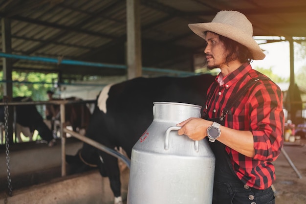 Agricultor que lleva un barril de leche pasa junto a la pequeña empresa de la granja de vacas lecheras