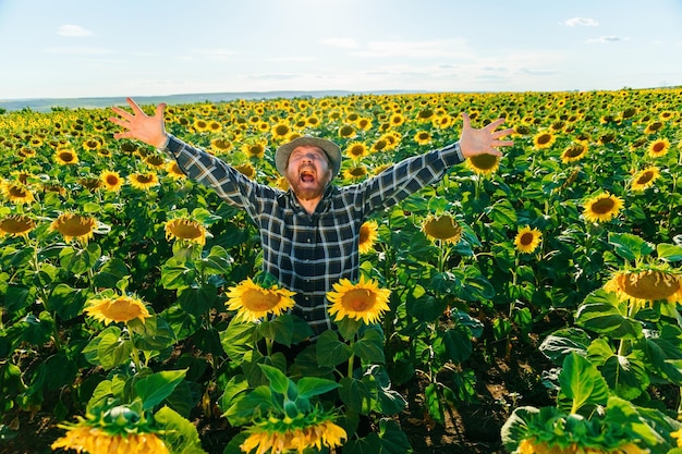 Agricultor sênior gritando em pé em terras agrícolas com braços levantados e alegre felicidade envelhecida