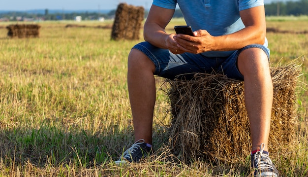 agricultor sentado em um campo com um telefone em um palheiro. em um campo com um telefone no palheiro.