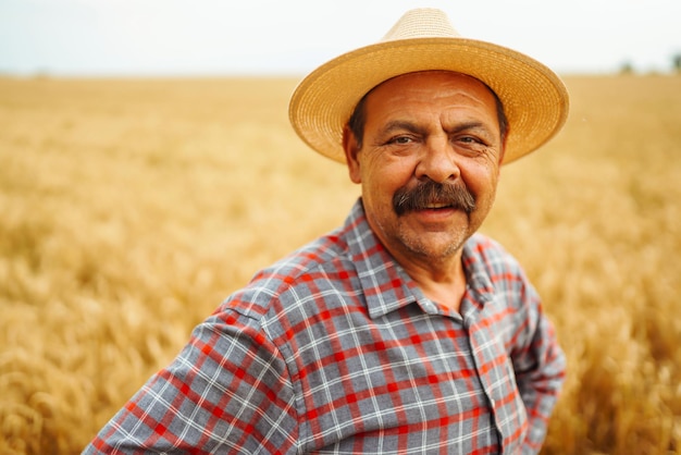 Agricultor en el sombrero en un campo de trigo control de cultivo Agricultura jardinería o concepto de ecología