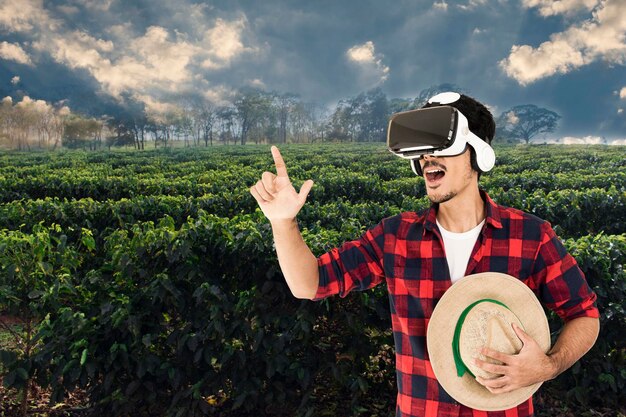 Foto agricultor con sombrero y gafas de realidad virtual en la imagen del concepto del paisaje de la plantación de café