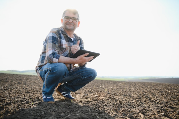 Un agricultor trabaja en un campo sembrado en primavera Un agrónomo camina por la tierra evaluando un campo arado en otoño Agricultura Tecnologías agrícolas inteligentes