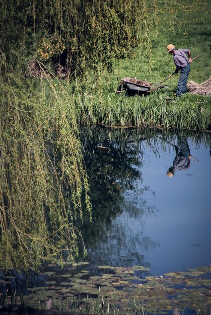 Agricultor trabajando por estanque en el campo