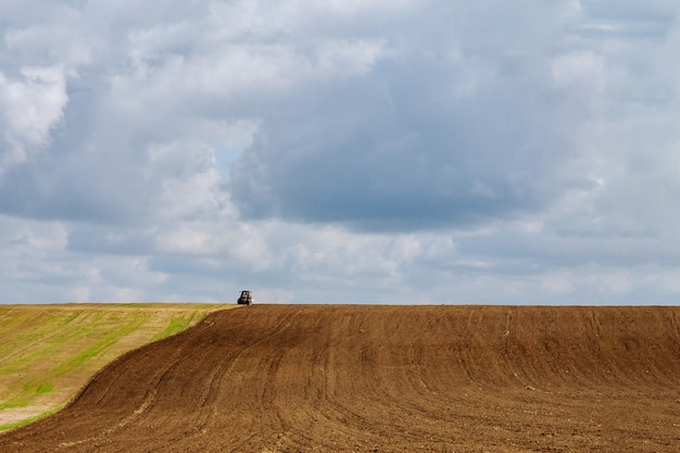 Agricultor en un tractor ara la tierra antes de sembrar con un cultivador de semillero