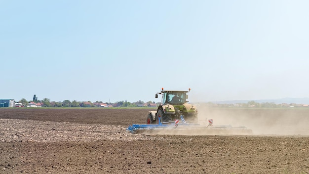 Agricultor en tractor preparando cultivador de semillero de tierra. Paisaje de tractor agrícola.