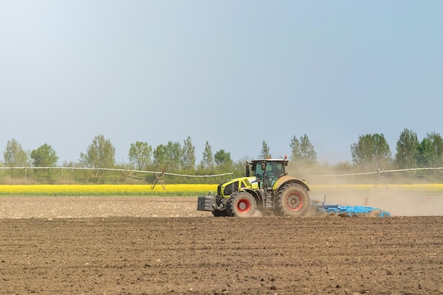 Agricultor en tractor preparando cultivador de semillero de tierra. Paisaje de tractor agrícola.