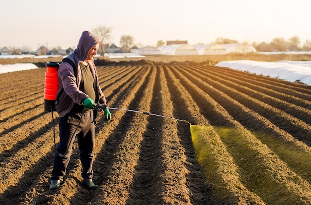 El agricultor trata el campo con malas hierbas y pasto para cultivar papas.Utiliza productos químicos en la agricultura.