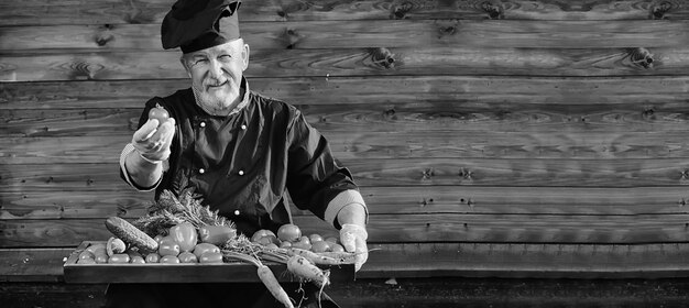 Agricultor en uniforme con verduras frescas sobre un fundamento de madera