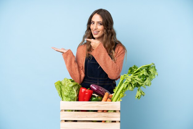 Agricultor con verduras recién cortadas en una caja con copyspace imaginario en la palma para insertar un anuncio