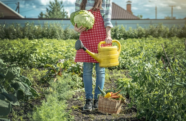 La agricultora agrónoma riega las plantas de una regadera amarilla en su jardín La alegría de cuidar tu granja