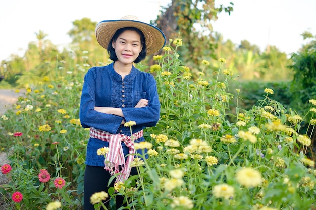 Agricultora asiática cruza os braços em pé no jardim de flores