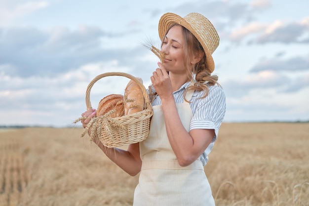 La agricultora de pie campo agrícola de trigo Mujer panadero sosteniendo una cesta de mimbre producto de pan